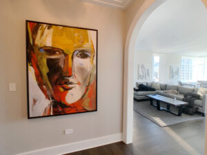 A hallway off the living room features a large framed art piece across from the curved archway. The art is an abstract of a person's face.