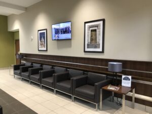 A waiting room with several leather chairs lined up against the wall. Three framed pictures hang on the wall above the chairs.