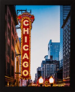 A black framed photograph of the Chase Chicago sign, street lights, and buildings all light up at dusk.