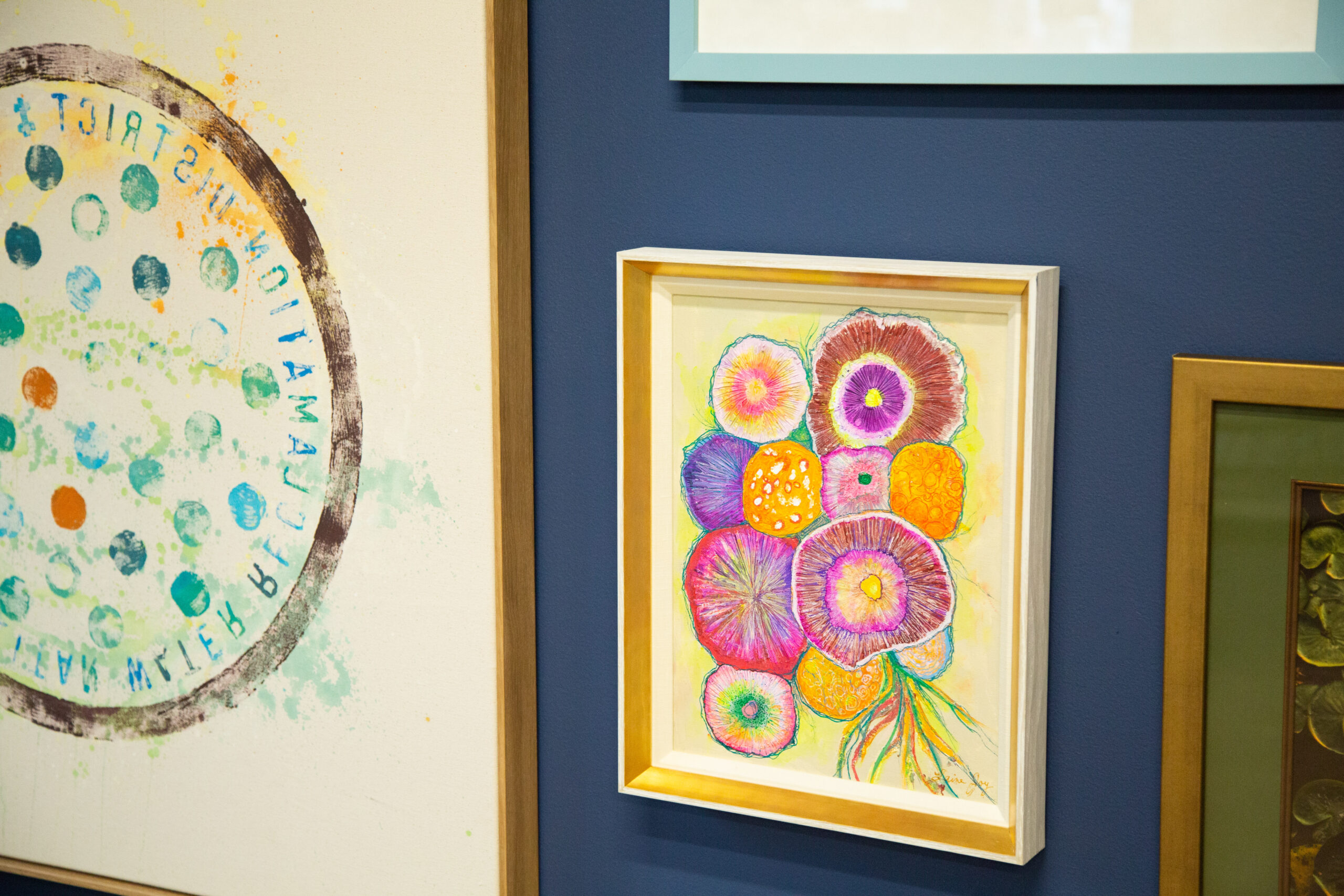 Peterson Picture framing example - a zoomed-in image of an art wall with two beautiful art pieces hung on the wall. One shows a drawn bouquet of colorful flowers and a second art piece.