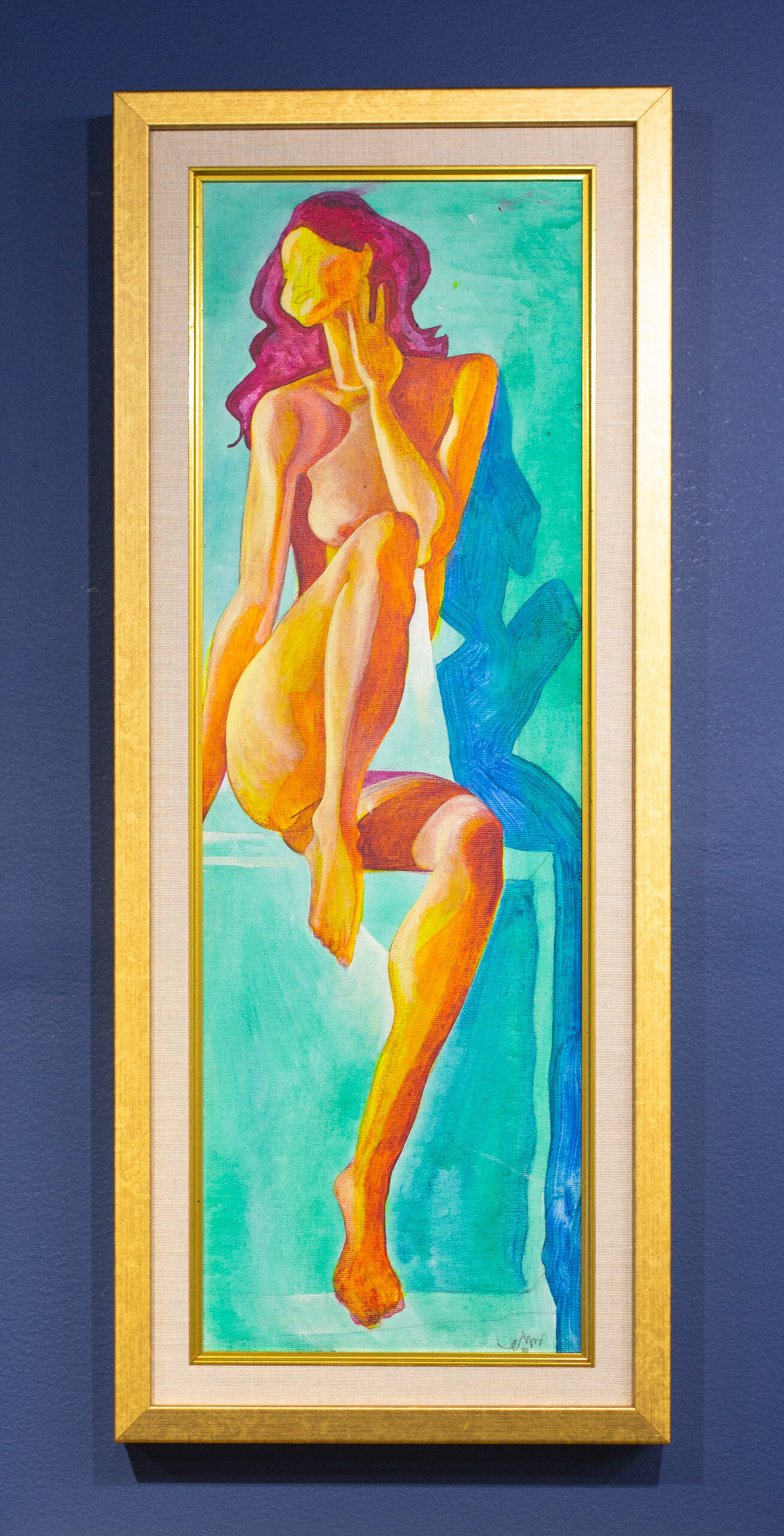 A closeup shows a colorful painting of a woman. The art is in a long vertical gold frame mounted on a Peterson Picture Co. gallery wall.