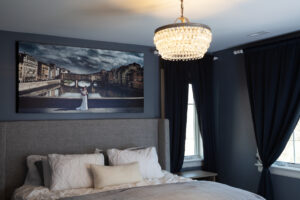 A large frame on the wall above a bed in a bedroom. Peterson Picture Co.'s extensive portfolio includes beautiful residential frames. Art on canvas.