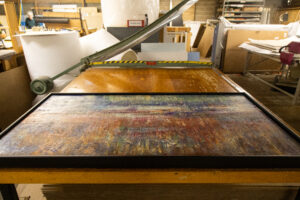 Peterson Picture handles with care art framing. The image shows a large, colorful abstract art piece is carefully framed and placed on a table in the Peterson Picture Co. facility.