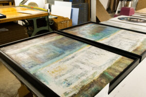 A close-up image of Peterson PIcture's fulfillment project - two oversized, colorful abstract art pieces that have been carefully framed and placed on a table in the Peterson Picture Co. facility.