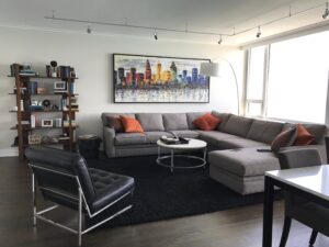 Peterson Picture has a vast experience in residential framin project. Here's an example of a large rectangular art piece of a colorful cityscape is framed and hung in a residential home. The large framed piece is placed on the wall above the couch.
